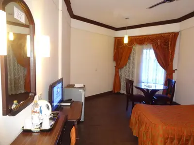 a hotel room with a bed and a desk with a television at Manuelsons Malabar Palace in Kozhikode