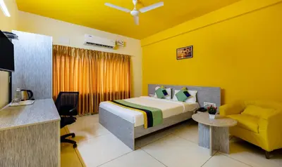 a hotel room with a bed and a chair at Treebo Four Seasons in Mysore