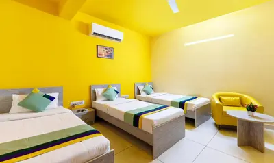 a room with two beds and a table and a chair at Treebo Four Seasons in Mysore