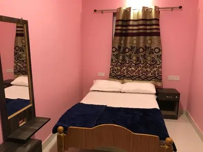 a small room with a bed and a mirror at HAPPYSTAY rooms and cottages in Ooty