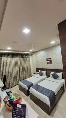 a hotel room with two beds and a table at Neermala Residency in Coimbatore