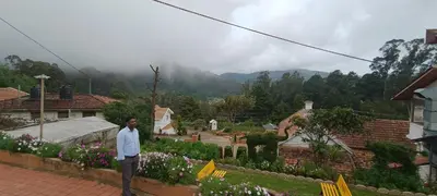 a man standing on a wall in a garden at Yantra Resort, Ooty in Ooty