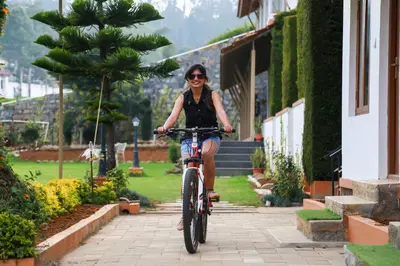 a woman riding a bike down a sidewalk at Yantra Resort, Ooty in Ooty