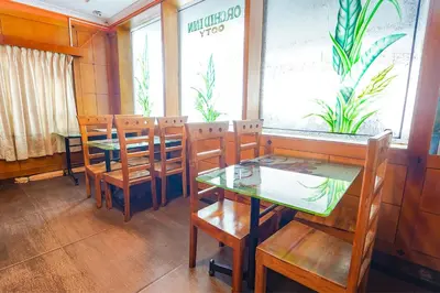 a dining room with tables and chairs in a restaurant at Hotel Orchid Inn in Ooty