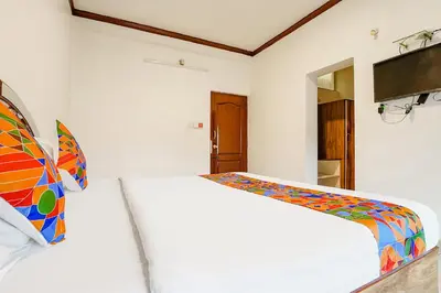 a bedroom with a white bed with a colorful blanket at Hotel Orchid Inn in Ooty