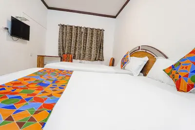 a hotel room with two beds and a flat screen tv at Hotel Orchid Inn in Ooty