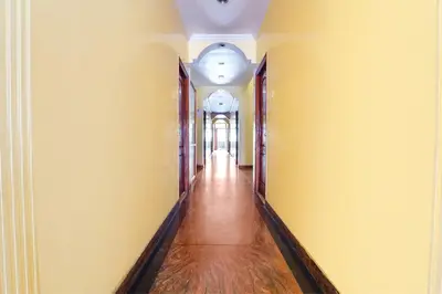 an empty hallway with yellow walls and wooden floors at Hotel Orchid Inn in Ooty