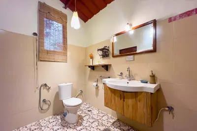 a bathroom with a toilet and a sink and a mirror at 5BR Firefly By The River with Breakfast - Nature's Lap in Kushālnagar