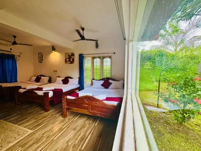 a bedroom with two beds and a large window at Coorg Nest Cottages By Dreamy Vacations in Kushālnagar