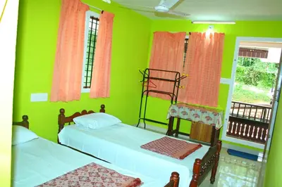 a green room with two beds and a window at Birds Song Homestay - Thattekadu in Ernakulam