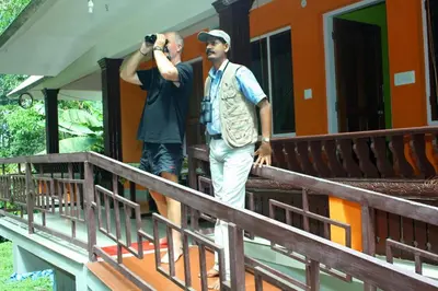 two men standing on a porch taking a picture with a camera at Birds Song Homestay - Thattekadu in Ernakulam