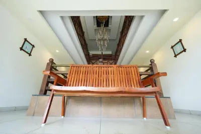 a wooden bench sitting in the middle of a room at Velan Temple View in Palani