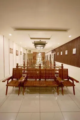 a large room with wooden benches in a building at Velan Temple View in Palani