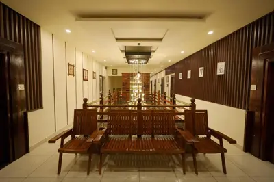 a row of wooden benches in a room with a row of tables at Velan Temple View in Palani