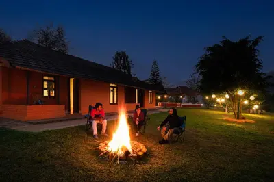 a group of people sitting around a fire in a yard at Zostel Homes Wayanad, Thirunelly in Wayanad
