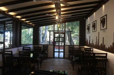 a dining room with tables and chairs and windows at VANYA by Citrine in Nelliyampathy