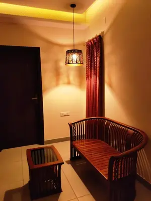 a living room with a bench and a chandelier at Sarvam Serviced Apartment in Coimbatore