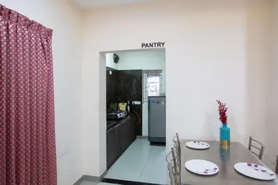 a dining room with a table and a kitchen at Sarvam Serviced Apartment in Coimbatore