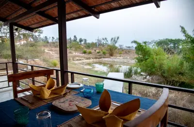 a table with a blue table cloth and a view of a river at Dhole's Den Bandipur in Bandipūr