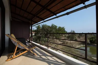 a chair sitting on a porch with a view of a field at Dhole's Den Bandipur in Bandipūr