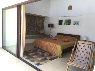 a bedroom with a bed and a person sitting in a window at Dhole's Den Bandipur in Bandipūr
