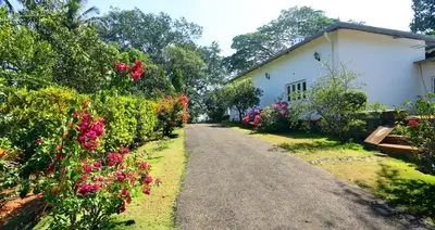 a road leading to a house with flowers at Parisons Plantation Experiences by Abad in Mananthavady