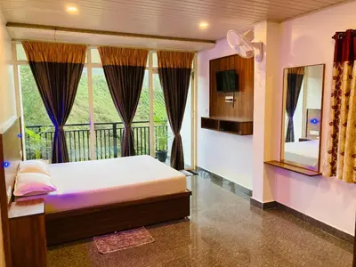 a bedroom with a bed and a large window at CARMEL HOME STAY in Munnar