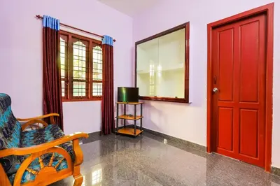 a room with a red door and a chair and a mirror at CARMEL HOME STAY in Munnar
