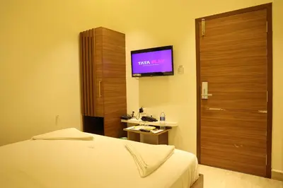 a hotel room with a bed and a flat screen tv at Hotel Amoha in Palani