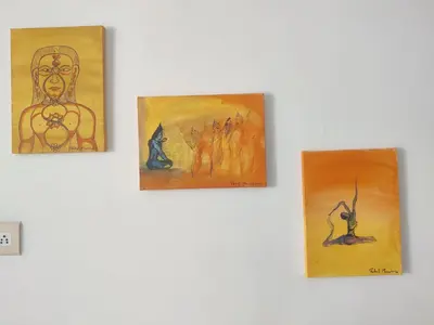 three paintings hanging on a white wall at Yoga House in Vānivilāsa Puram