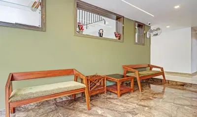 a room with two beds and a table and a window at Sreepathi Mayoogha in Guruvāyūr