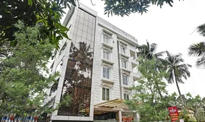 a large white building with trees in front of it at Sreepathi Mayoogha in Guruvāyūr