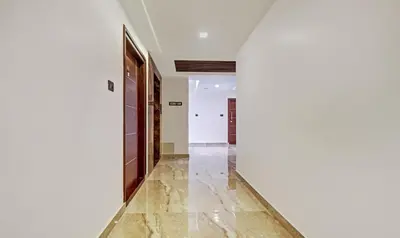 a hallway with white walls and marble flooring at Sreepathi Mayoogha in Guruvāyūr