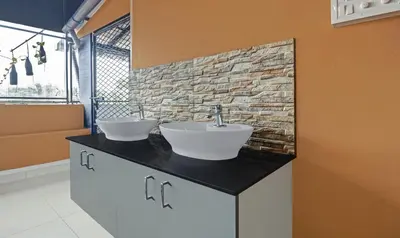 a bathroom with two sinks and a brick wall at Sreepathi Mayoogha in Guruvāyūr