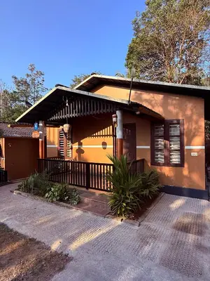 a small yellow house with a porch at Wayanad Cocos Villa in Tariyod