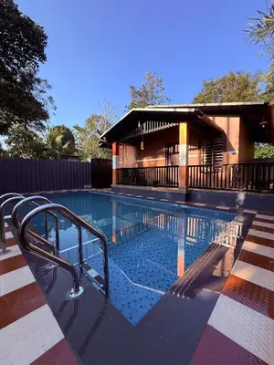 a swimming pool with a resort building in the background at Wayanad Cocos Villa in Tariyod