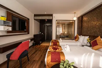 a hotel room with two beds with red chairs and a television at Saugandhika West Gate in Wayanad