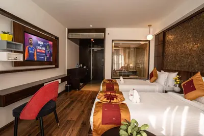 a hotel room with a large bed with red chairs at Saugandhika West Gate in Wayanad
