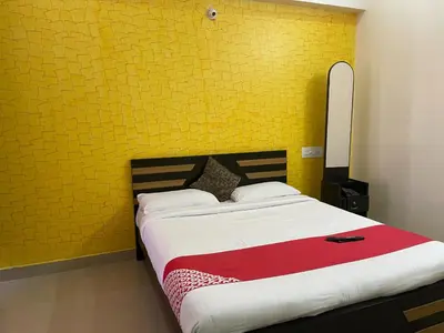 a bedroom with a large bed with a yellow wall at Green Valley Residency in Gundlupet