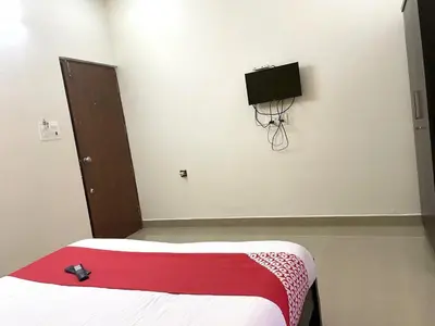 a bedroom with a bed and a tv on the wall at Green Valley Residency in Gundlupet