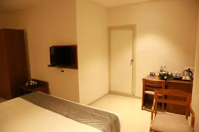 a bedroom with a bed and a desk and a television at Hotel Picnic in Manjeri