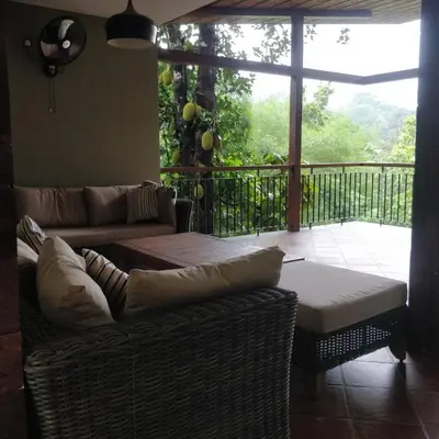 a living room with two couches and a balcony at BARSATI Ranches in Vythiri
