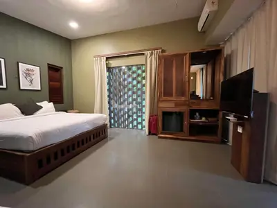a bedroom with a bed and a flat screen tv at BARSATI Ranches in Vythiri