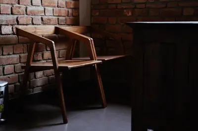a wooden chair sitting next to a brick wall at BARSATI Ranches in Vythiri