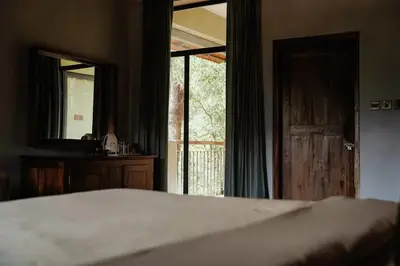 a bedroom with a bed and a mirror and a door at BARSATI Ranches in Vythiri