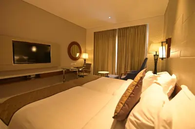 a hotel room with a large bed and a flat screen tv at Hotel Amaravathi in Mandya