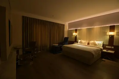 a hotel room with a bed and a desk and a chair at Hotel Amaravathi in Mandya