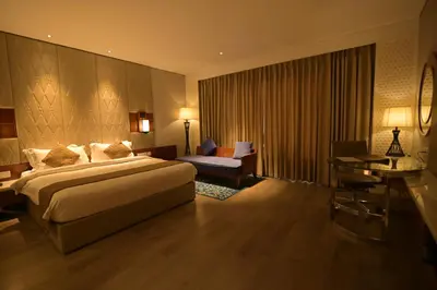a large hotel room with a bed and a desk at Hotel Amaravathi in Mandya