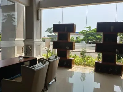 a lobby with a desk and chairs and a large window at Hotel Amaravathi in Mandya