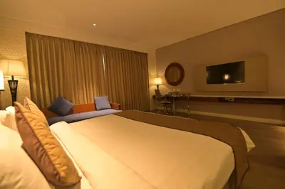 a hotel room with a bed and a flat screen tv at Hotel Amaravathi in Mandya